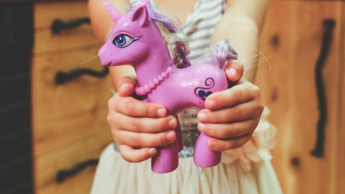 hands-purple-child-holding child holding unicorn toy